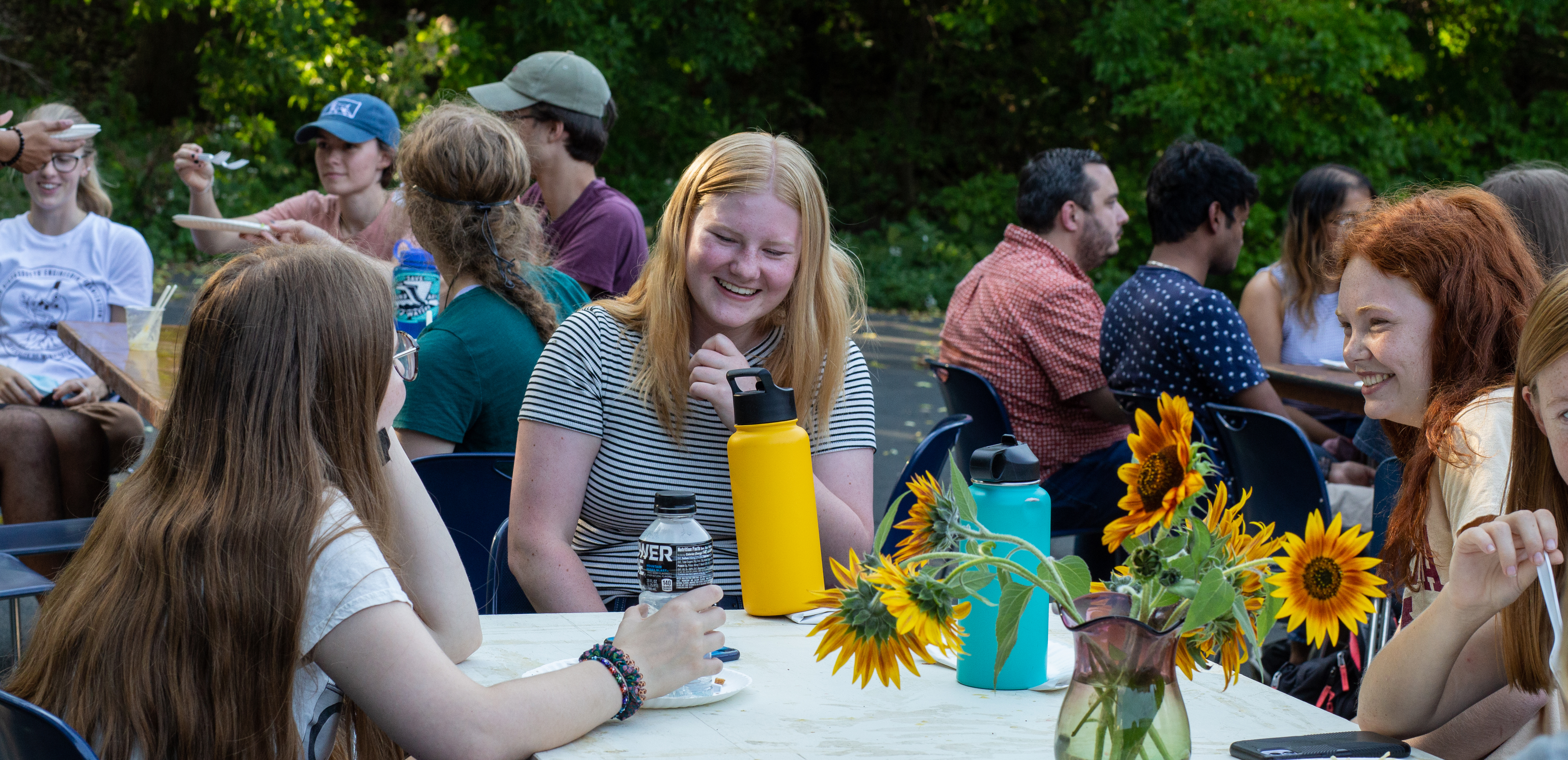 Students gather at table at the annual BBE BBQ and are seen sharing a laugh